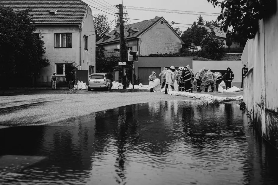 Responders placing sandbags along a flooded street to hold back flood water